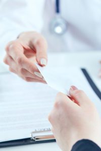 Close up of person's hand presenting health insurance card to health care worker.