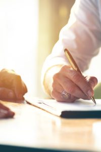Man signing a document in the presence of others.