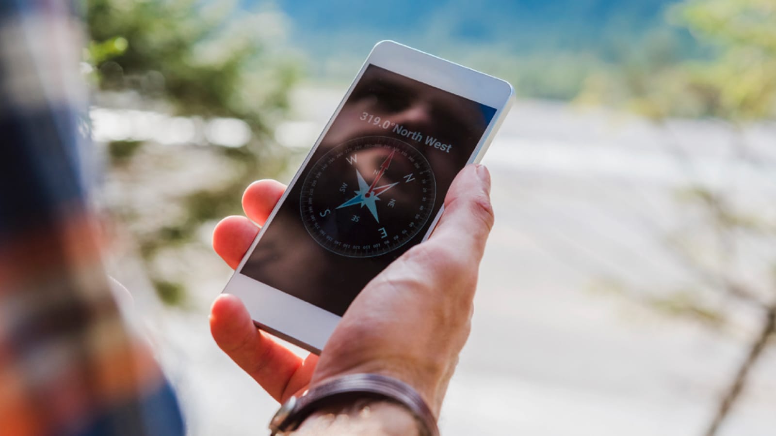 outdoor-apps-large Hiker looking at a compass on their smartphone