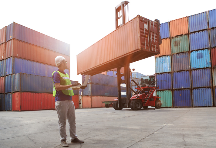 Engineering working and he is loading container for support logistics and import export business Worker Monitoring Loading Container Being Lifted