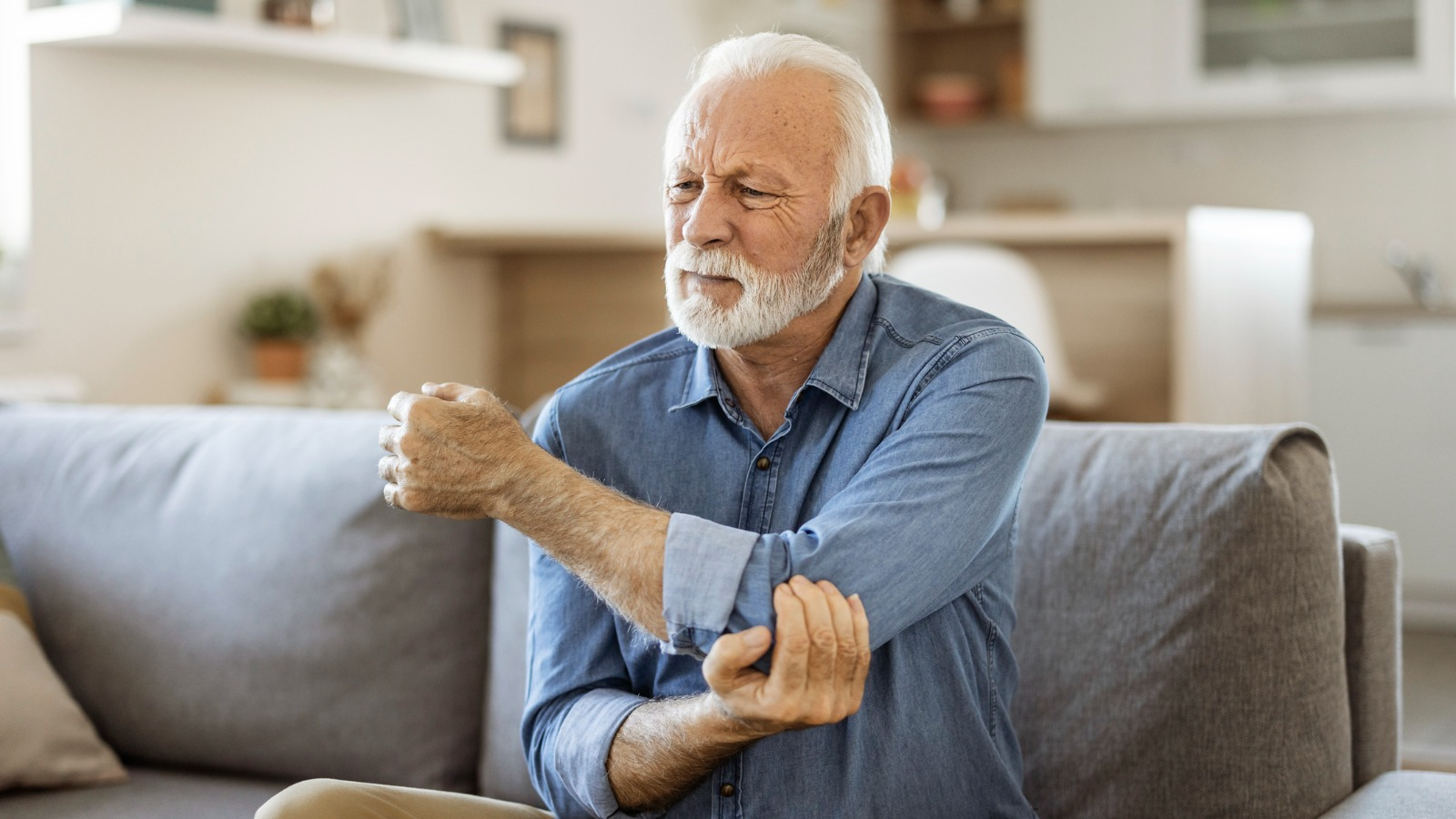 Man in pain holding arm elder man holding elbow