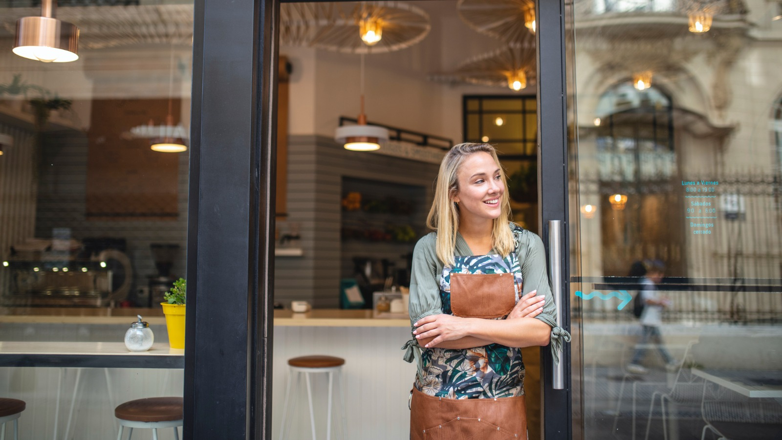 new business owner outside smiling Woman standing outside of her cafe