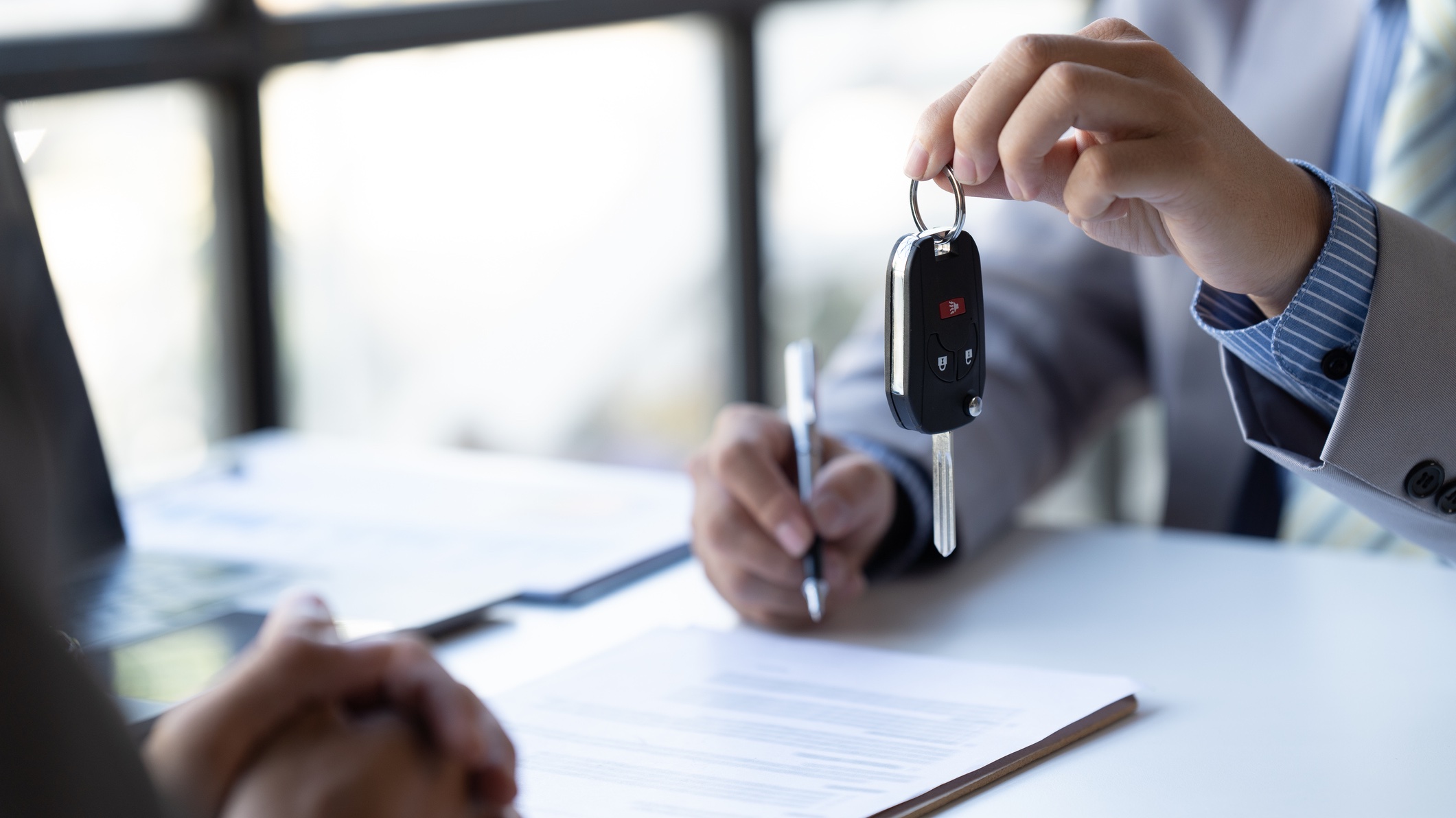 signing paperwork to a new car salesperson handing over keys