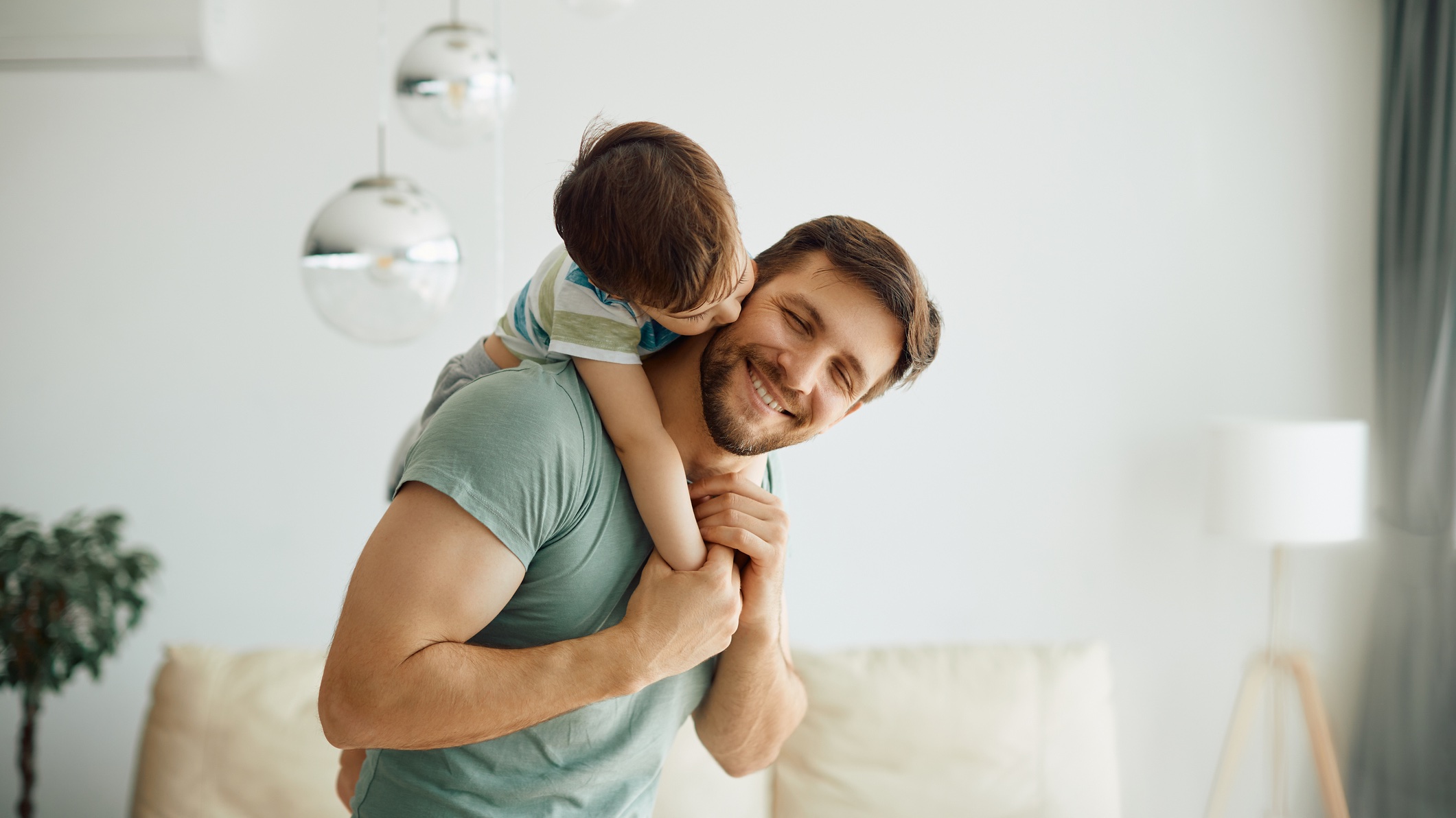 Young son on dad’s back smiling Father and Son playing together