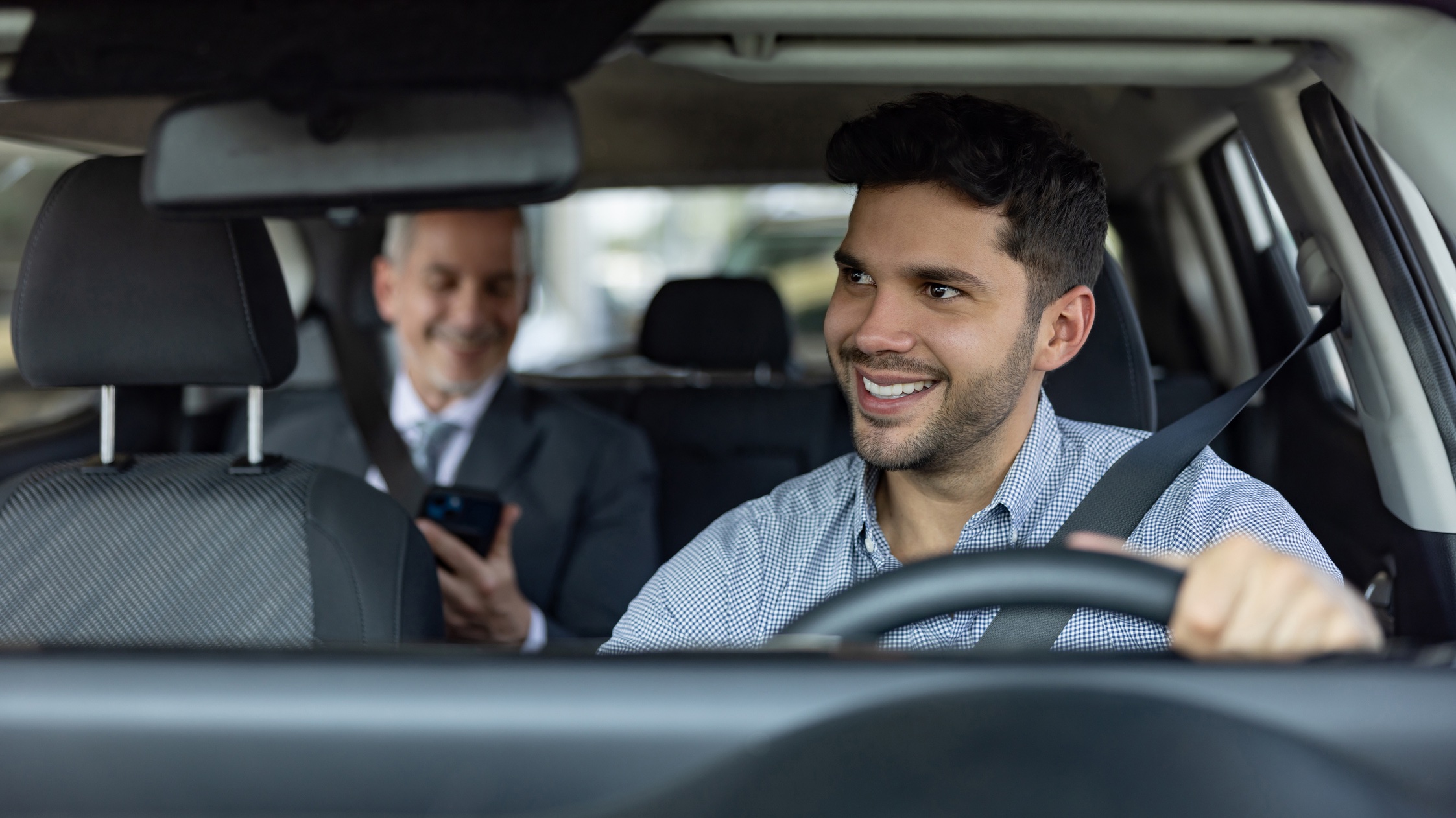Rideshare man driving senior male Rideshare driver smiling at passenger
